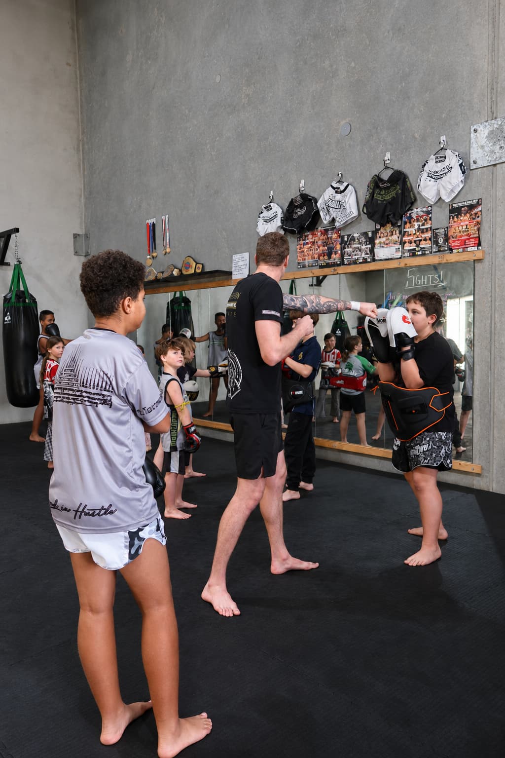 Cameron coaching a kid on pad work — Bioweaponites class